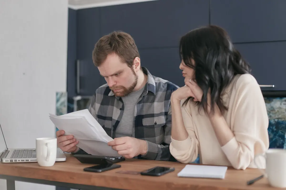 Pareja revisando con preocupación las cláusulas abusivas de su contrato de preventa en la mesa de su casa