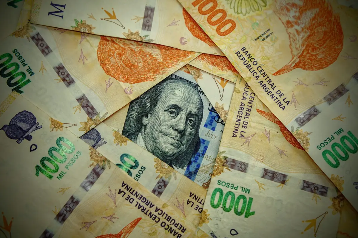 Billetes de mil pesos argentinos y un dólar, el dinero que un argentino convierte para comprar propiedad en México
