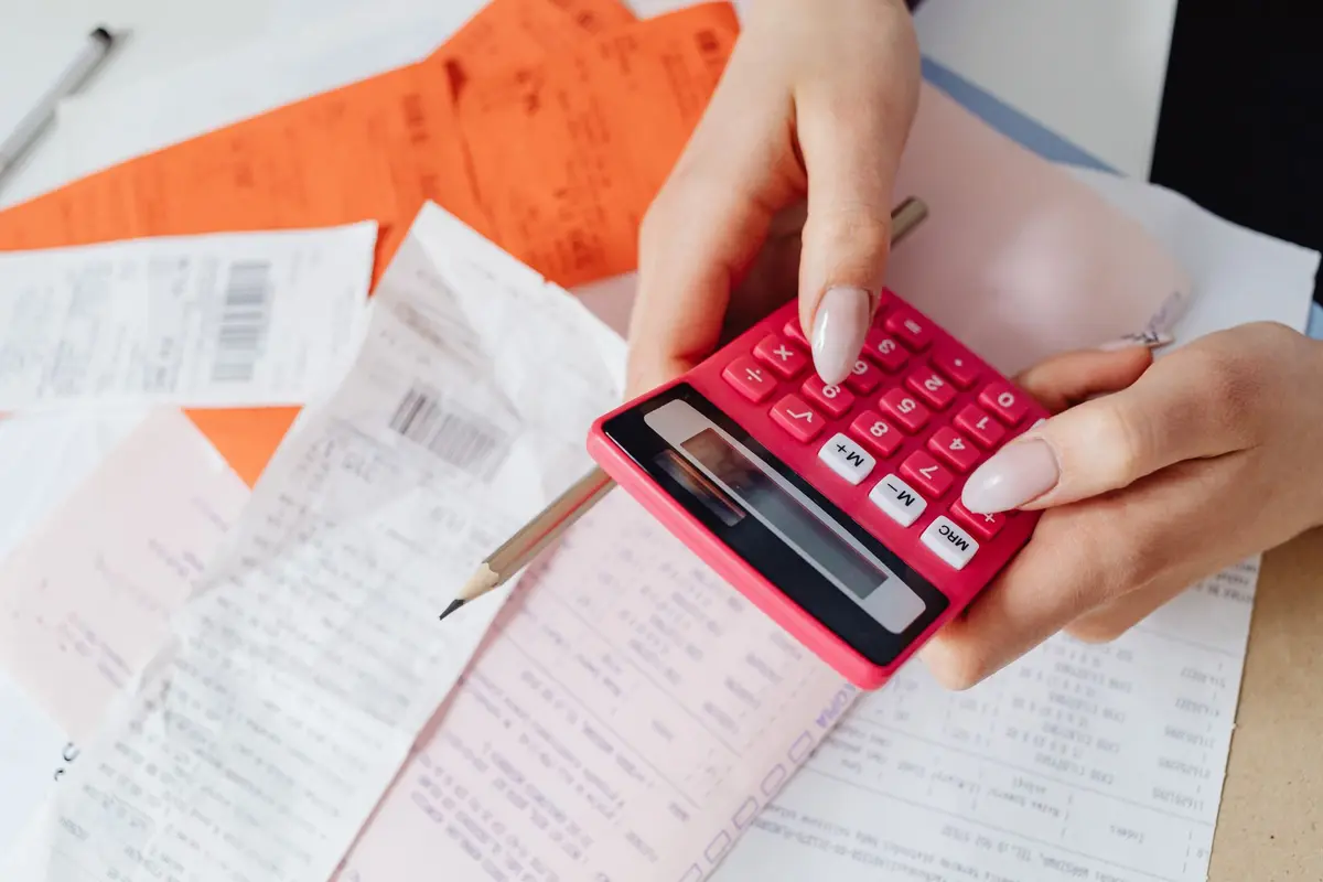 Manos con calculadora sobre recibos, cálculo del adeudo de morosos en las cuotas de condominio