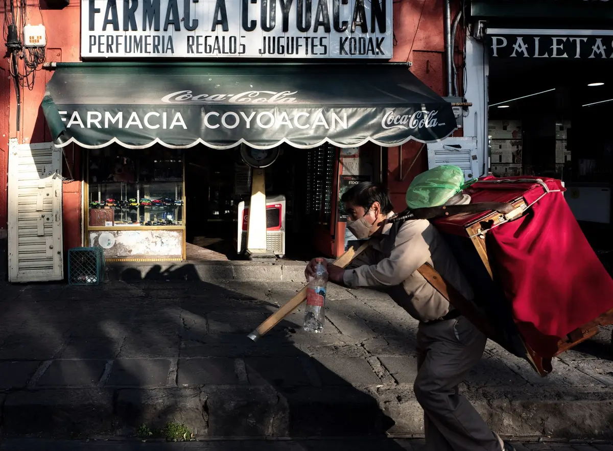 Calle del centro de Coyoacán con una farmacia tradicional y un vendedor, ambiente de barrio al vivir en Coyoacán